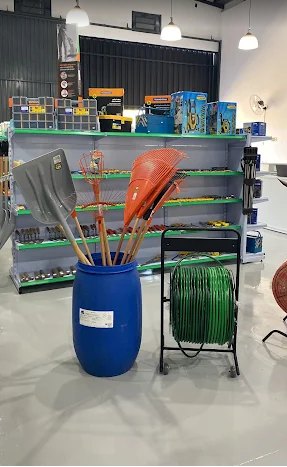 Ferramentas de jardinagem, rastelos e mangueira em enrolador